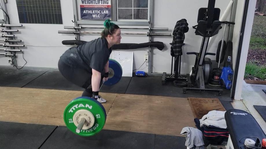 A woman sets up for a clean with the Eleiko IWF Weightlifting Training Bar.