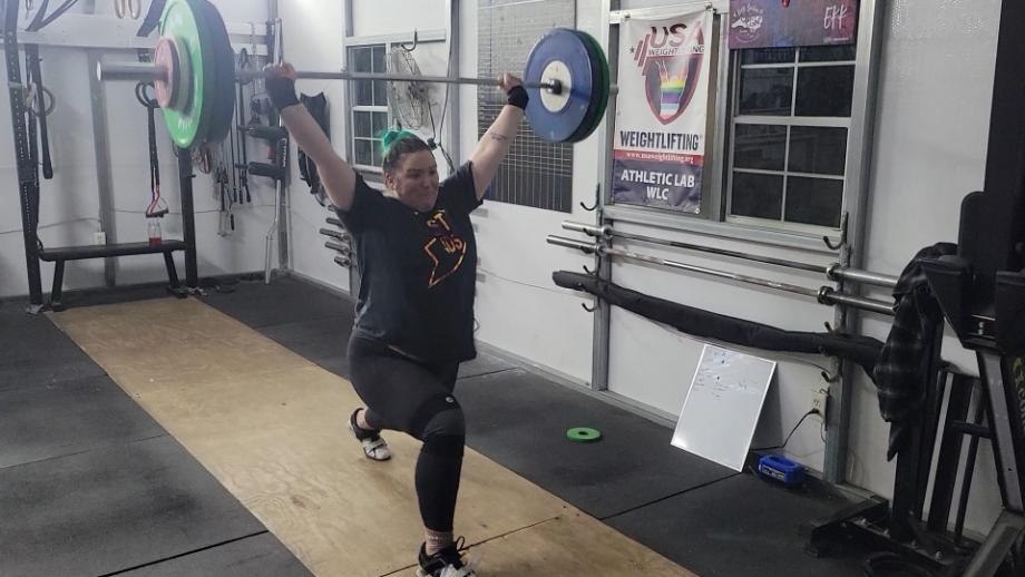 A woman performs a barbell clean with the Eleiko IWF Training Bar.