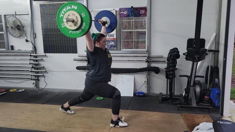 A woman performing a barbell jerk with the Eleiko IWF Weightlifting Training Bar.