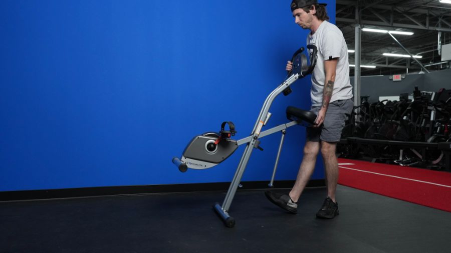 An image of a man moving the Exerpeutic folding magnetic exercise bike