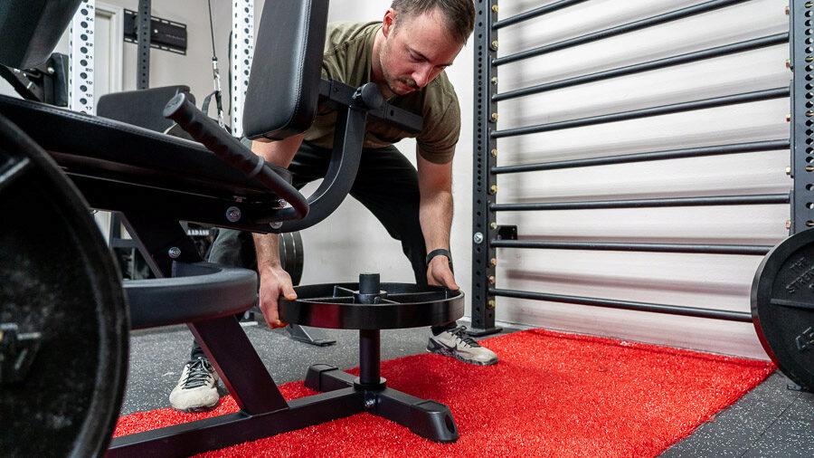 Coop placing weight on balance for the Titan Seated Leg Curl/Extension 