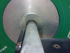 An image showing the Rogue Ohio Bar in a J-cup with a green weight plate on the end