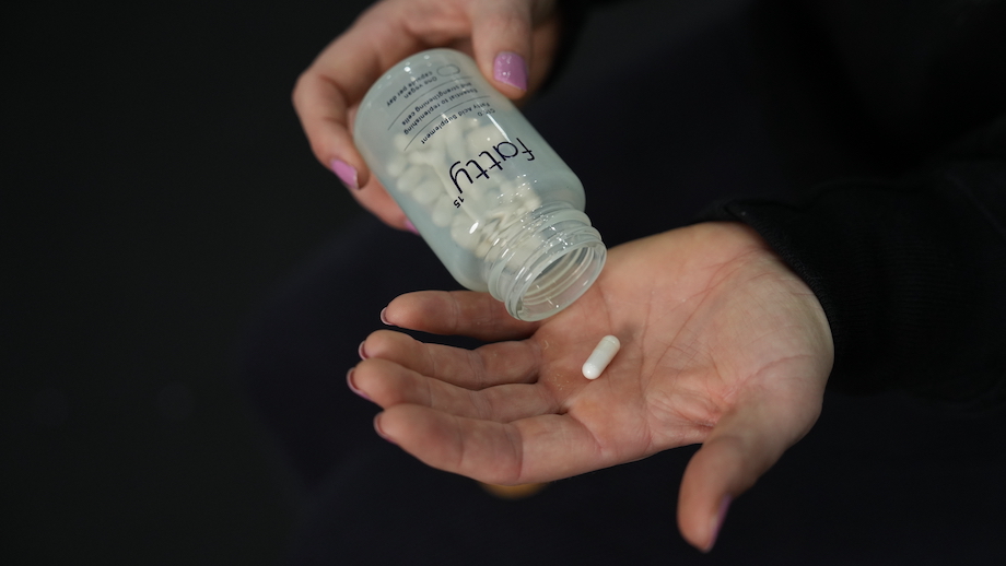 An image for the Fatty15 review of a woman holding a capsule in her hand