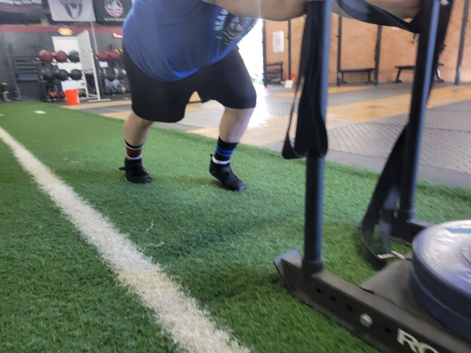 Man performing sled pushes with the Xero Shoes Forza Trainers