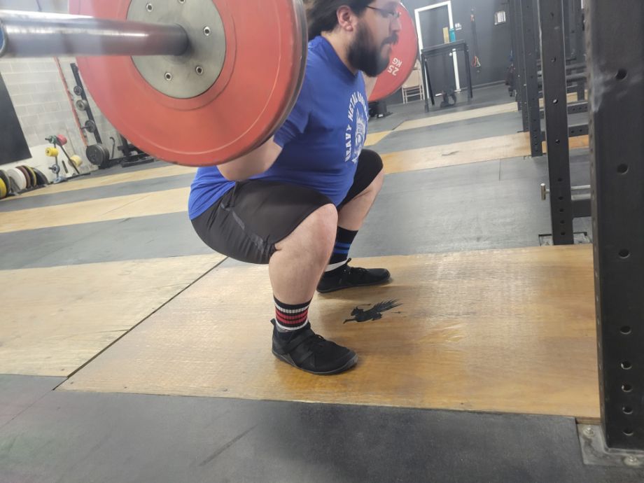 Man squatting with the Xero Shoes Forza Trainers