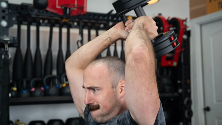 Man performing a French press holding onto the steel support rods of the REP Fitness QuickDraw Adjustable Dumbbells