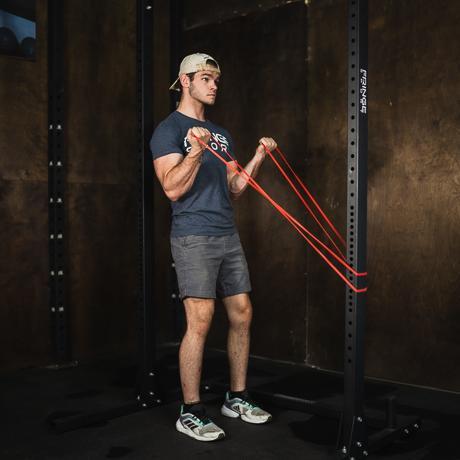 man using red fringe sports latex free resistance band for bicep curls