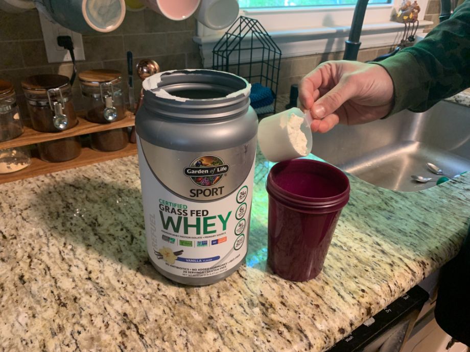 Garden of Life Grass Fed Whey protein powder being scooped into shaker bottle