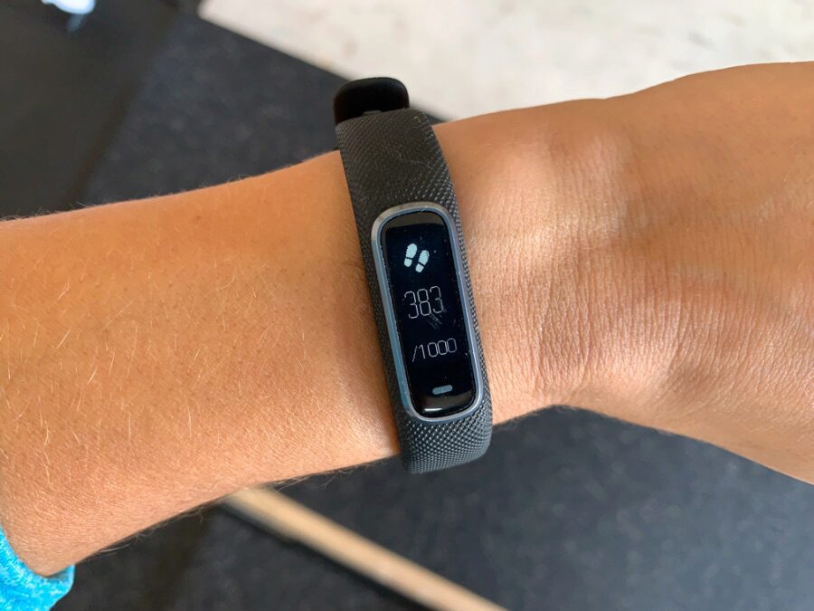 The Garmin Vivosmart 4 screen shows step count.