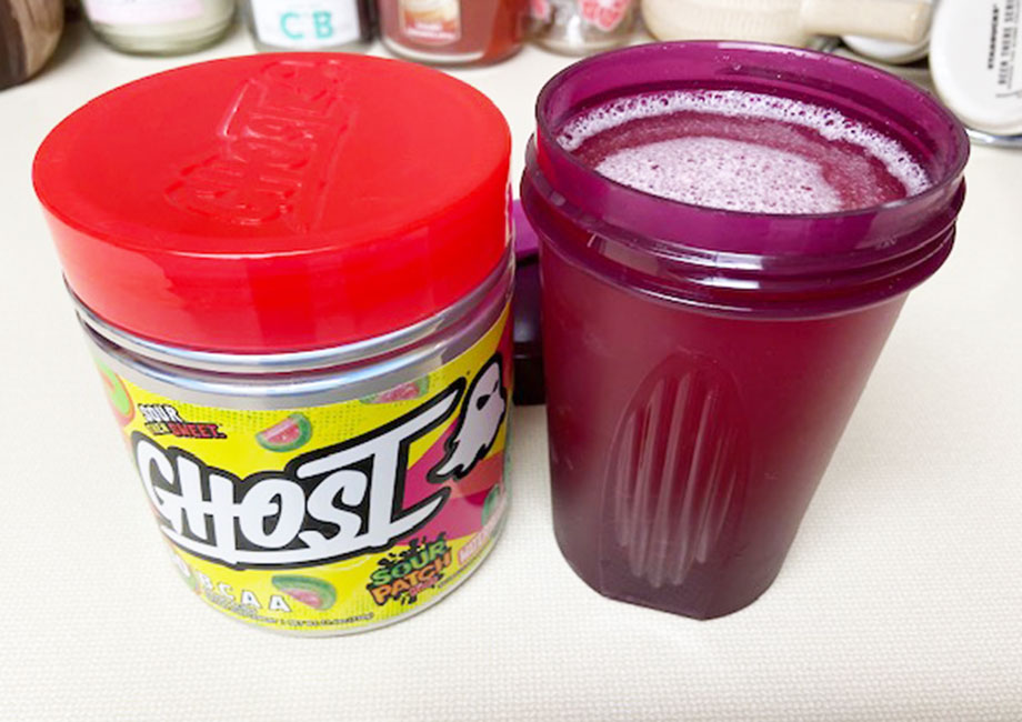 A Ghost BCAA container sits next to a full shaker cup