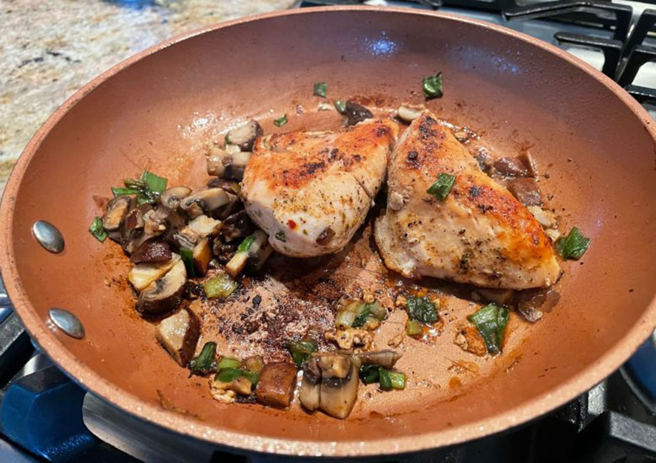 chicken breast and vegetables being cooked in a pan