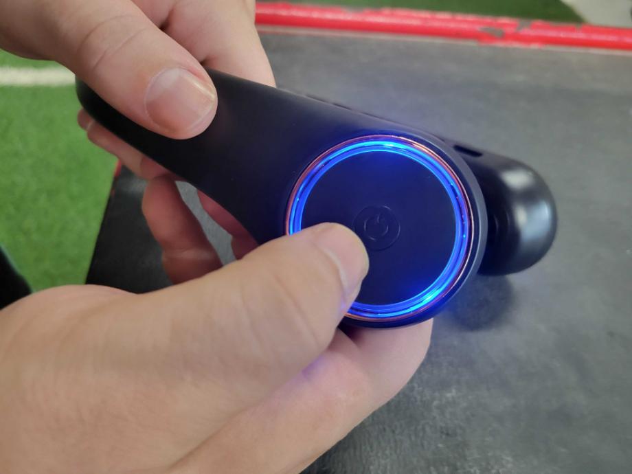 A person handles and showcases the power button and auto-changing lights of the GULAKI Neck Fan