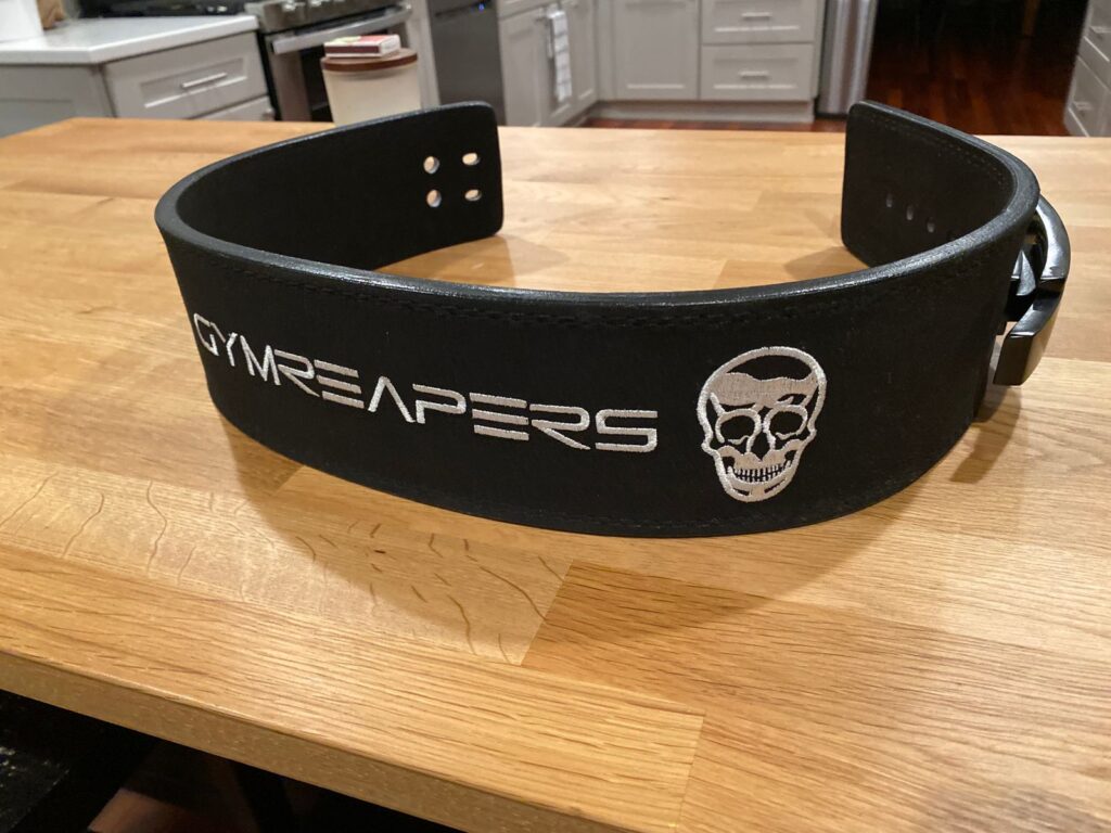 Black Gymreapers level belt, unbuckled and sitting on a table.