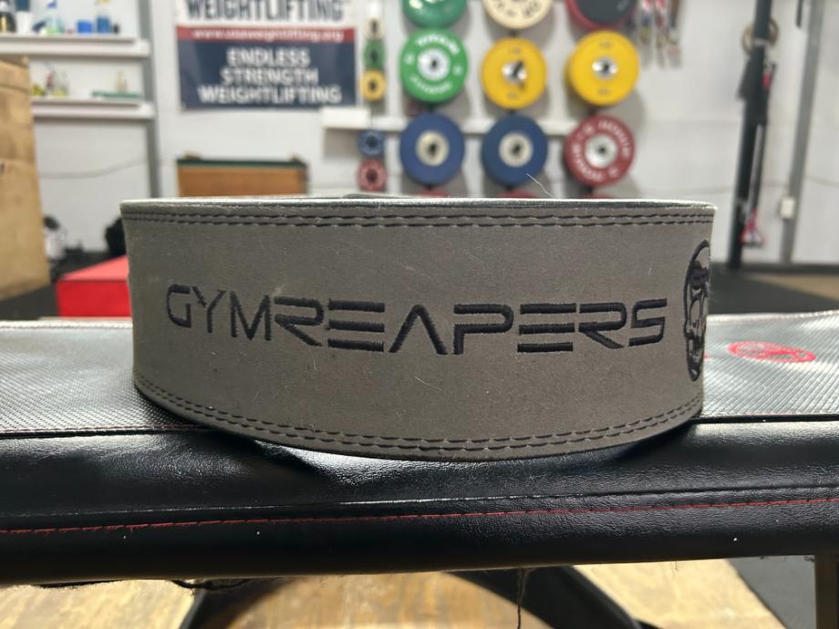 A close up view of the Gymreapers Lever Belt resting on a weight bench.