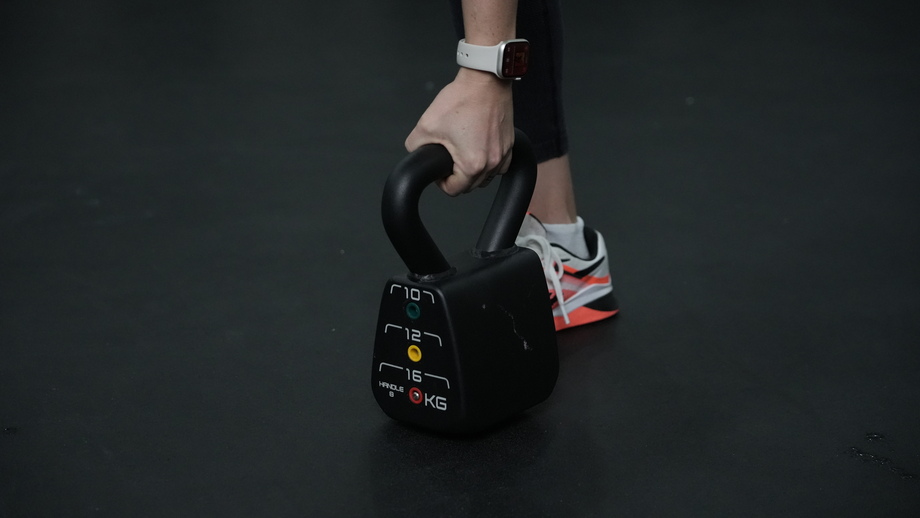 A hand is shown holding the PowerBlock Adjustable Kettlebell.