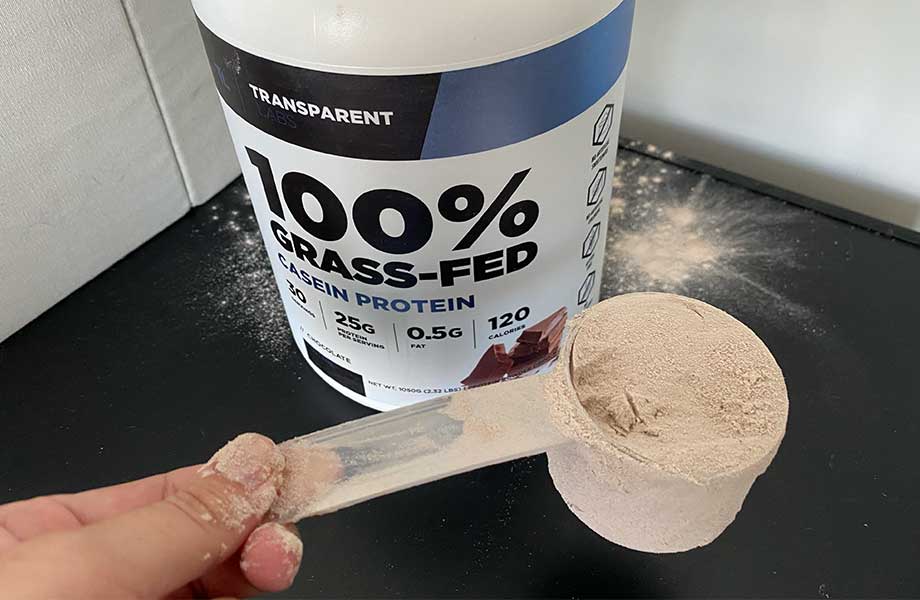 Looking down on a hand holding a scoop of Transparent Labs Casein Protein powder.
