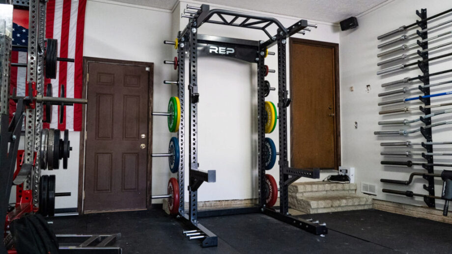 A home gym with a REP fitness rack, weight plates, and barbells. 