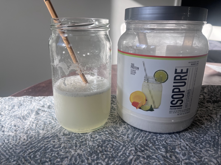 Isopure Clear Whey protein is shown mixed in a glass next to the container.