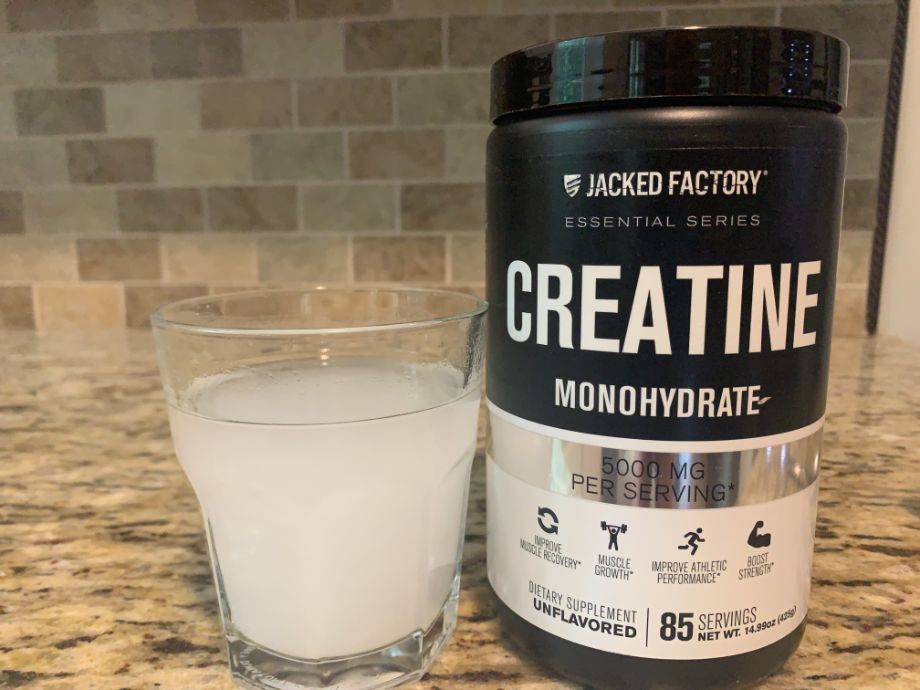 A freshly mixed glass of Jacked Factory Creatine next to the container.