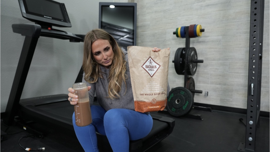 Woman holding Ka'Chava Shake while reading nutritional information on the bag