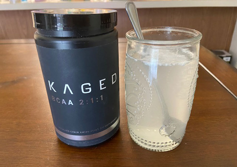 A mixed glass of Kaged Muscle BCAAs stands next to the container.