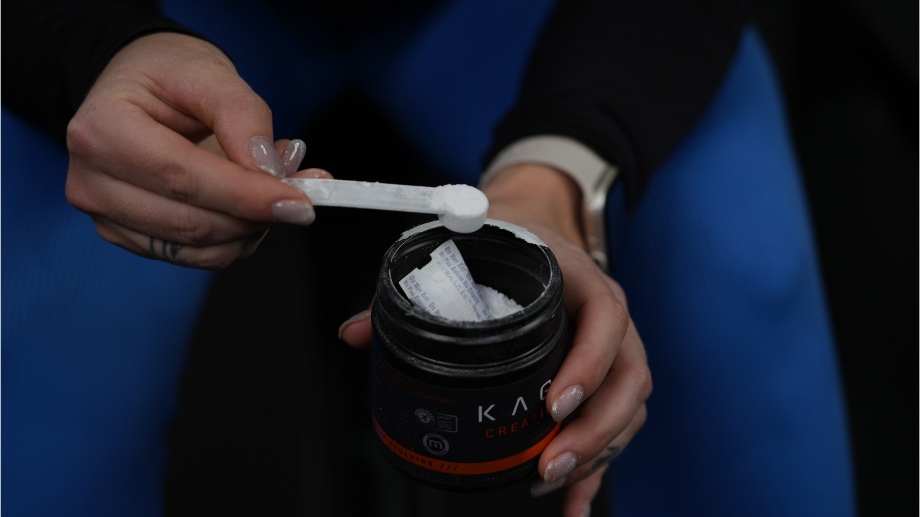 A close up view of someone scooping Kaged Creatine HCl from the container.
