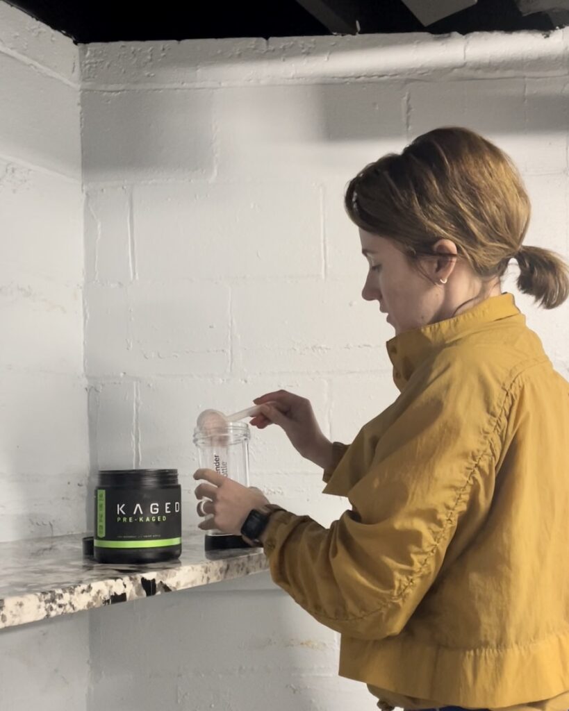 An image of a woman mixing Kaged Pre-Kaged pre-workout in a shaker