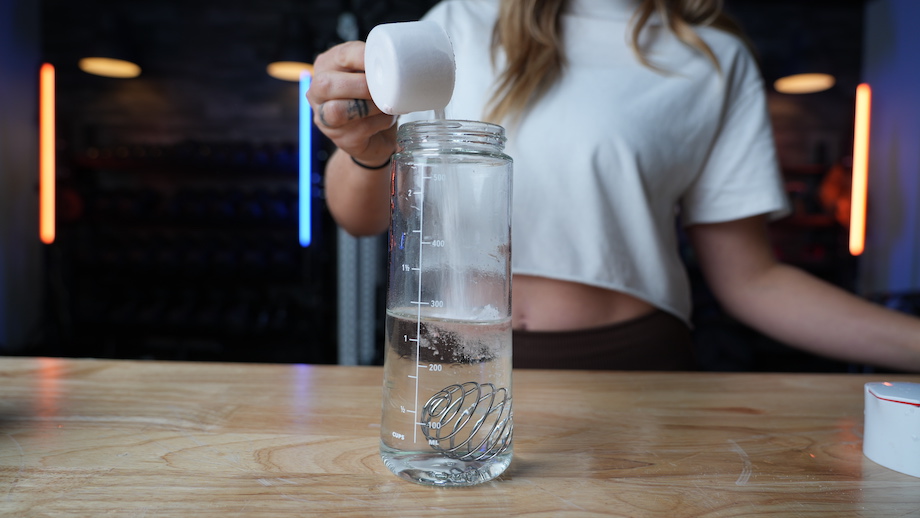 Image of woman pouring Kaged Pre-Kaged stim-free pre-workout into shaker