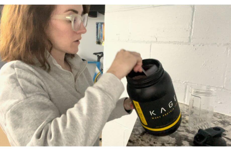 kaged protein powder, woman scooping protein powder from bottle