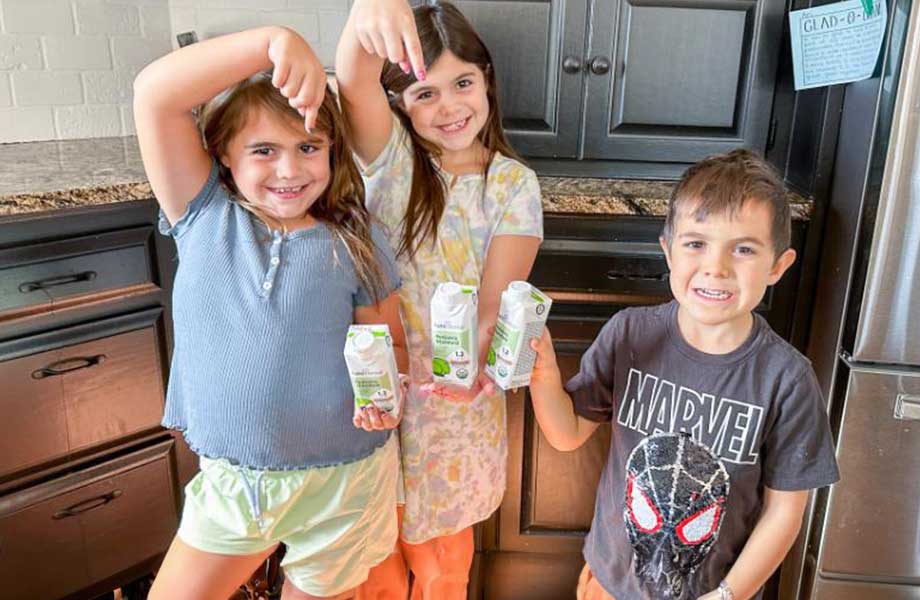 3 kids hold up Kate Farms protein shakes