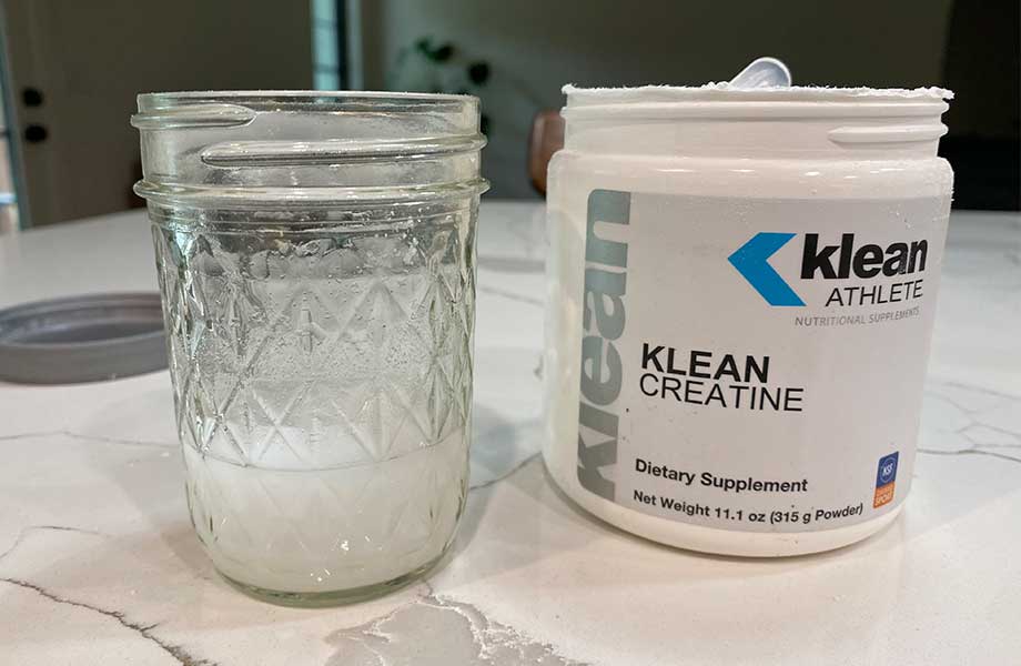 A glass of Klean Creatine is mixed next to the container