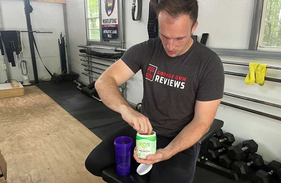 Man scooping KOS Greens powder into a shaker