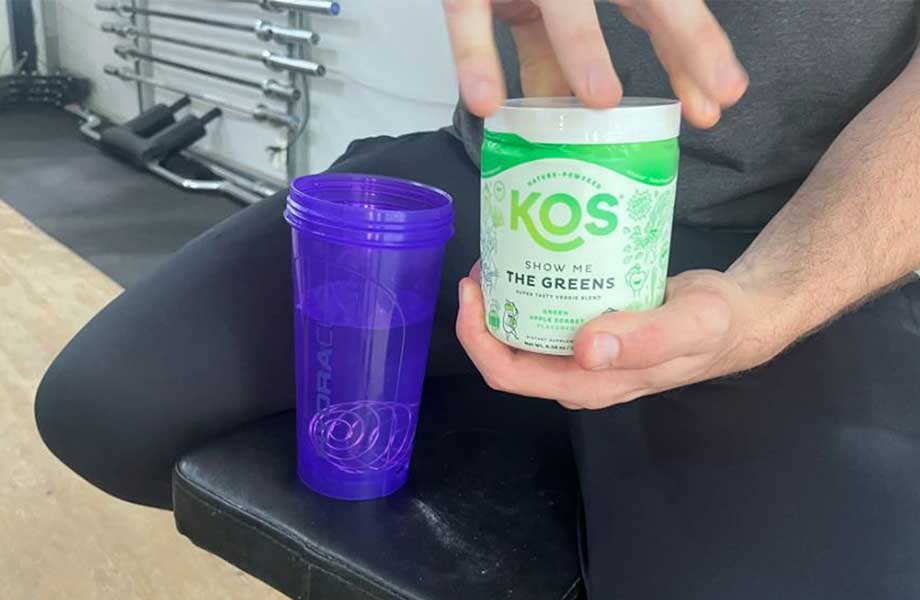 Close-up image of someone holding a container of KOS Show Me the Greens