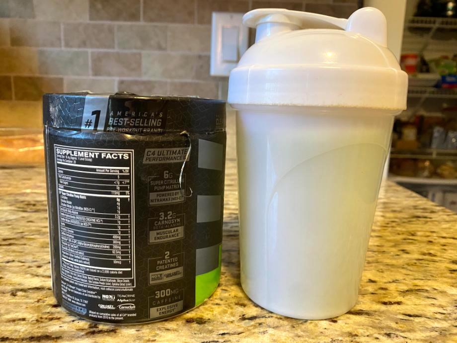 A can of C4 Ultimate Pre-Workout sits next to a shaker cup with the Supplement Facts label displayed
