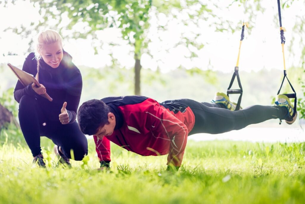 a woman training a man to do elevated push-ups in a park