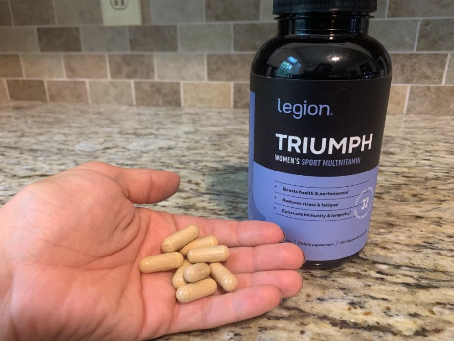 Woman holding pills from Legion Triumph women's multivitamin