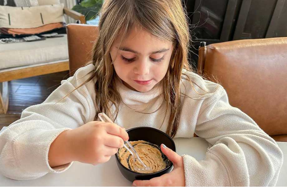 A little girl eating PB&Me powdered peanut butter protein