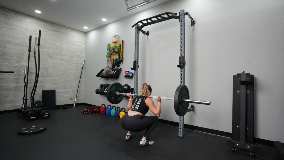 A woman performs a back squat with the Living.Fit Barbell
