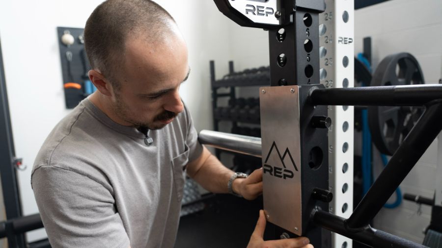 Man adjusting a REP Fitness rack attachment