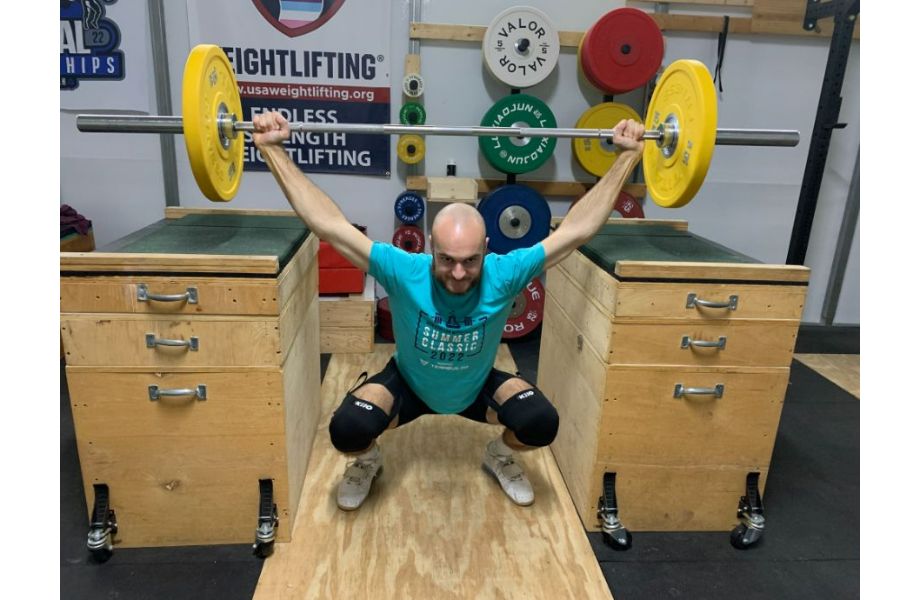 man doing overhead squat with 1 kilo sleeves