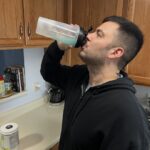 A person is shown drinking an IsoWhey protein shake.