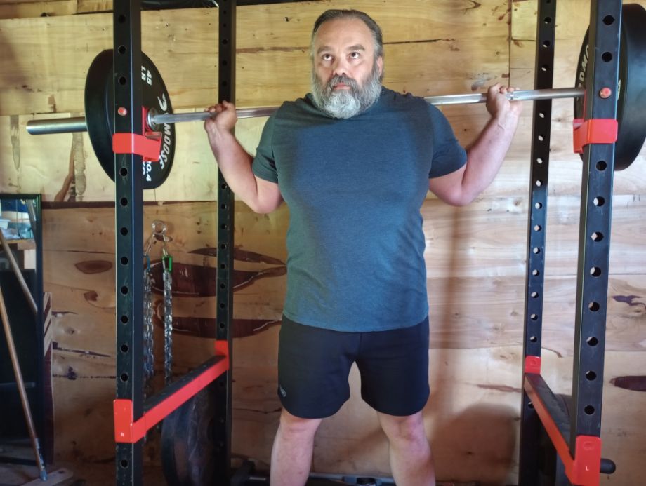 Person holding a DMoose Regional Barbell in rack