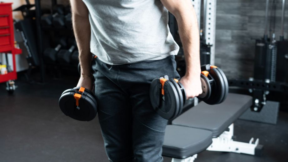 Man holding dumbbells at side