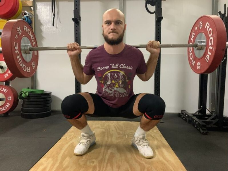 man squatting with sbd knee sleeves