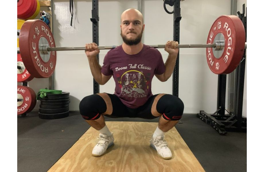 man squatting with sbd knee sleeves