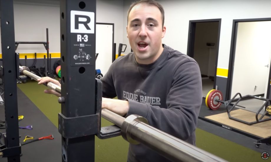 man standing with a barbell in a rack
