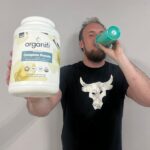 Man drinking Organifi Complete Protein and holding the container
