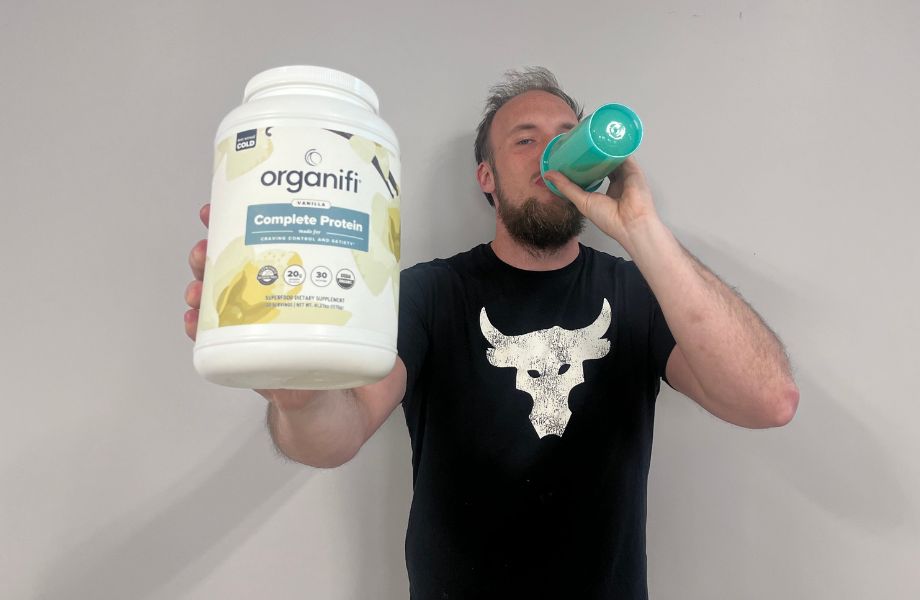 Man drinking Organifi Complete Protein and holding the container