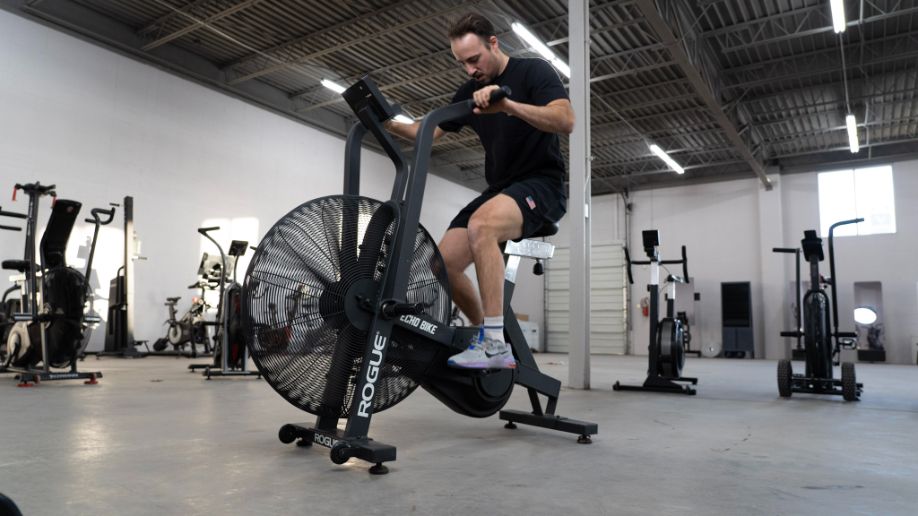 man riding rogue echo bike in home gym