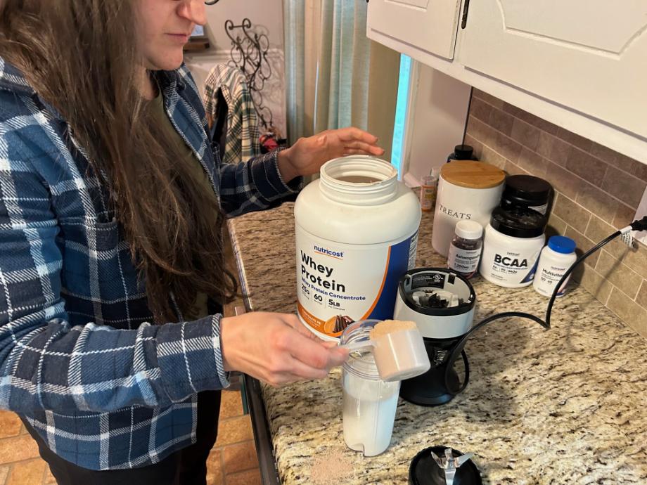 woman mixing Nutricost Whey Concentrate into a shake